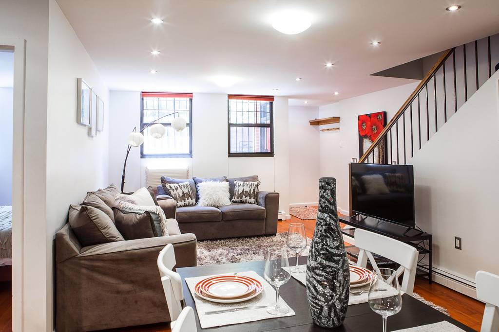 153 Stanton Street, Unit A1 Manhattan, NY 10002 - Photo 7 of 16 a living room with furniture and a flat screen tv