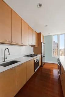 a kitchen with stainless steel appliances granite countertop a sink a stove a refrigerator with wooden cabinets and floors