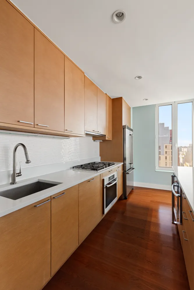 a kitchen with stainless steel appliances granite countertop a sink a stove a refrigerator with wooden cabinets and floors