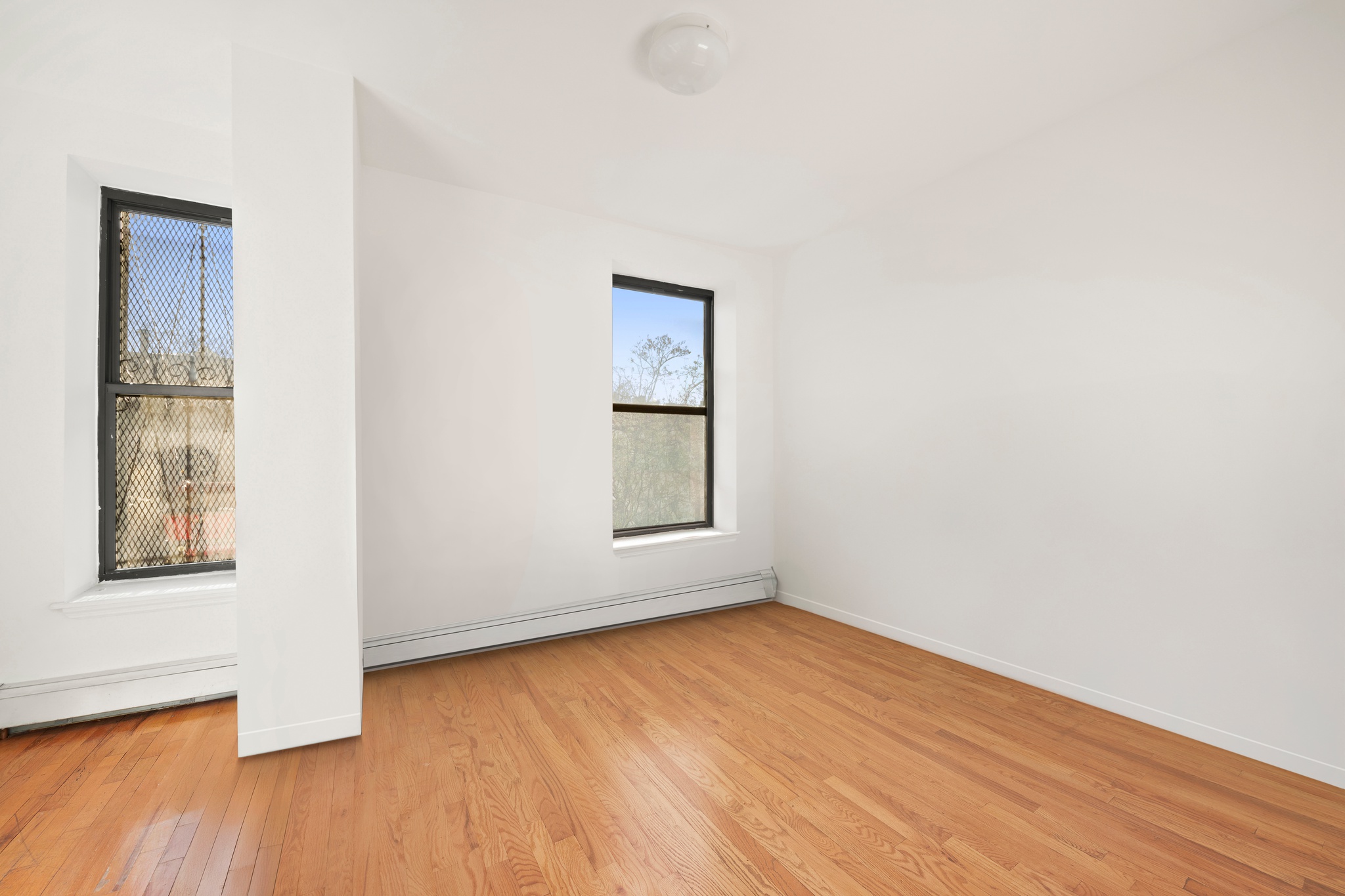 522 West 149th Street, Unit 3 Manhattan, NY 10031 - Photo 3 of 7 an empty room with wooden floor and windows