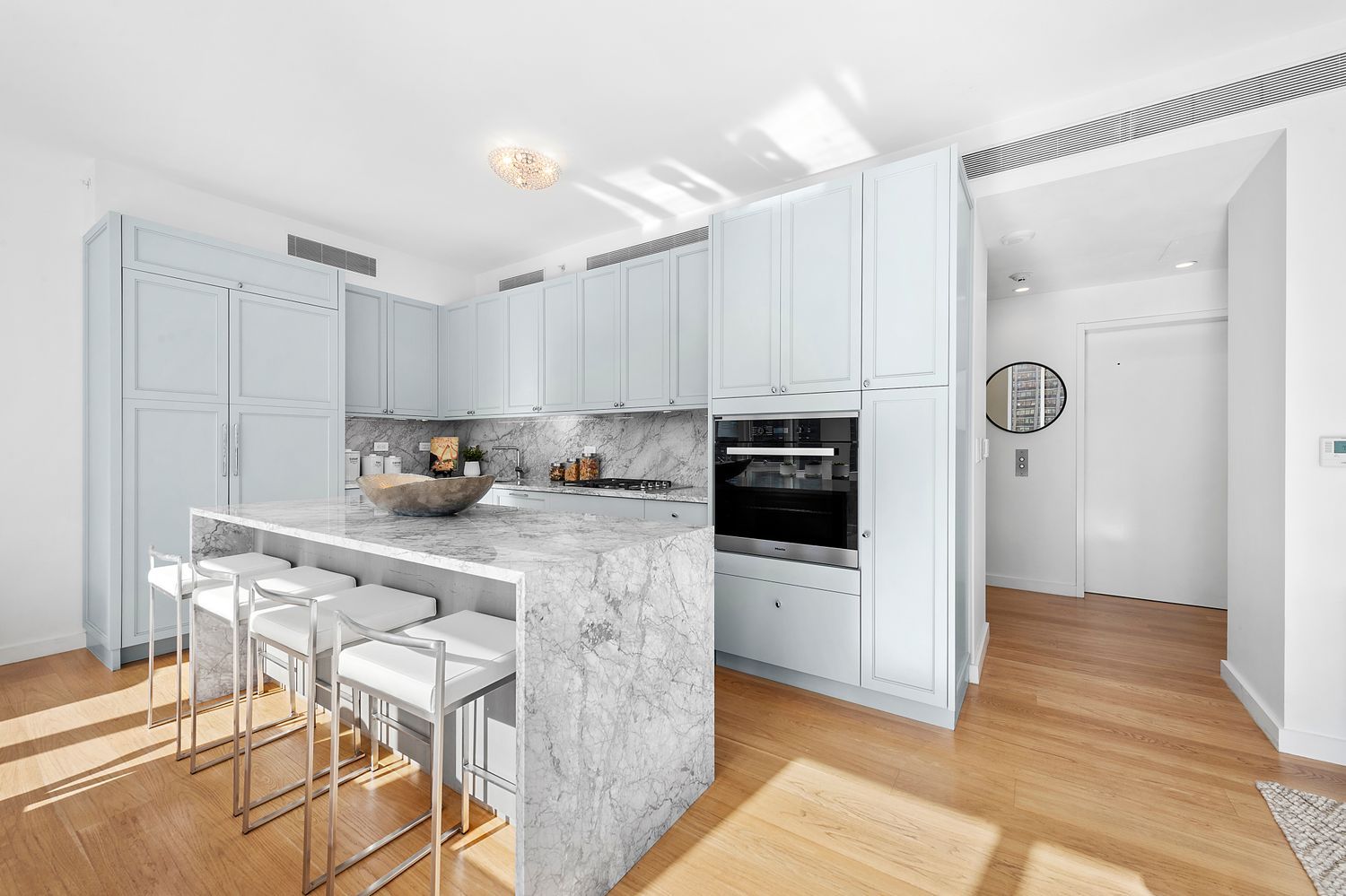 301 East 61st Street, Unit 16A Manhattan, NY 10065 - Photo 6 of 17 a kitchen with stainless steel appliances kitchen island granite countertop a refrigerator a stove a sink and white cabinets with wooden floor