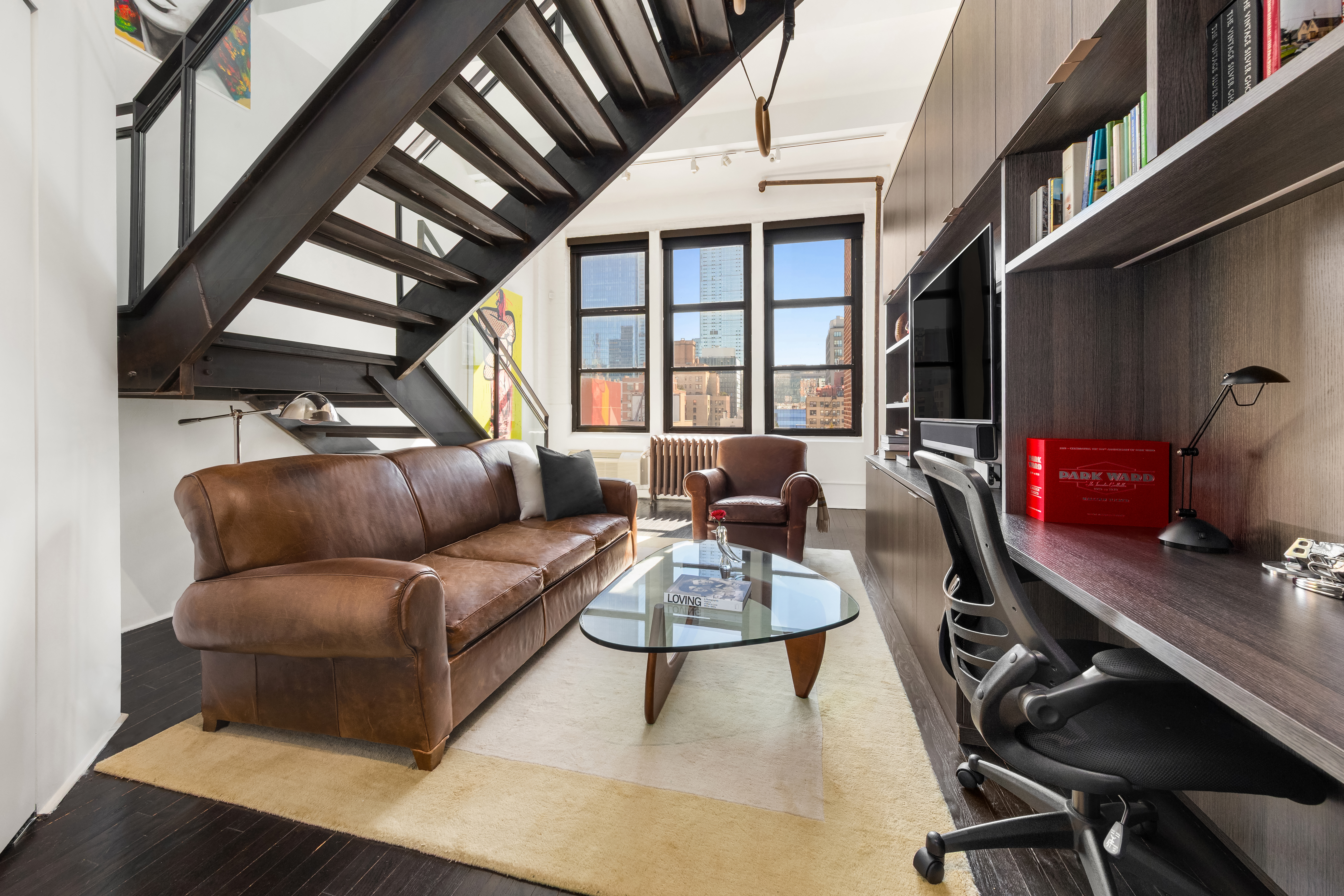 448 West 37th Street, Unit 11G/12G Manhattan, NY 10018 - Photo 9 of 17 a living room with furniture a flat screen tv and a window