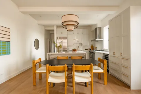 a dining hall with stainless steel appliances granite countertop a stove and a dining table with wooden floor