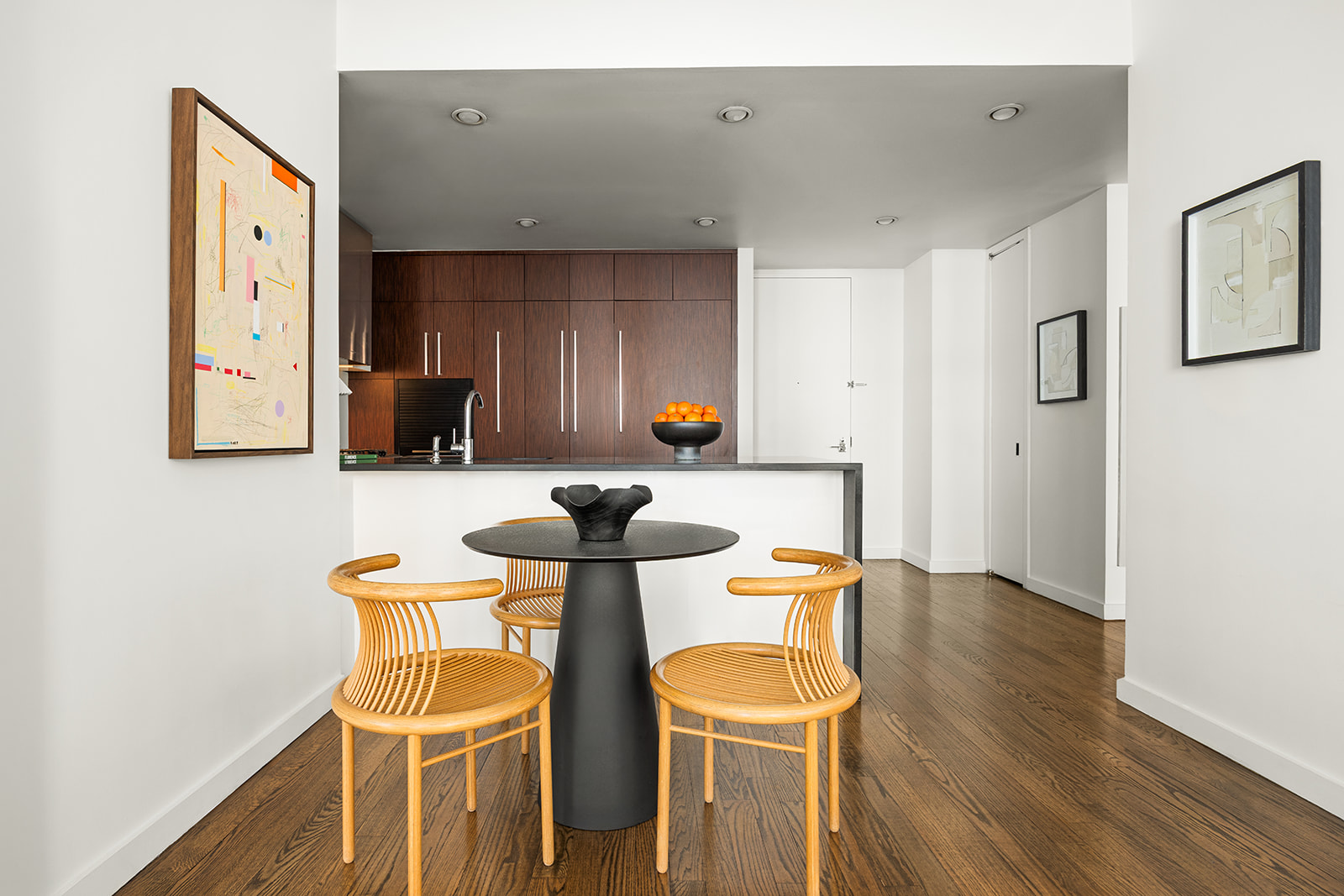 133 West 22nd Street, Unit 8G Manhattan, NY 10011 - Photo 4 of 16 a kitchen with stainless steel appliances kitchen island granite countertop a dining table chairs and a refrigerator