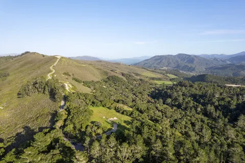 a view of a mountain range with lush green forest