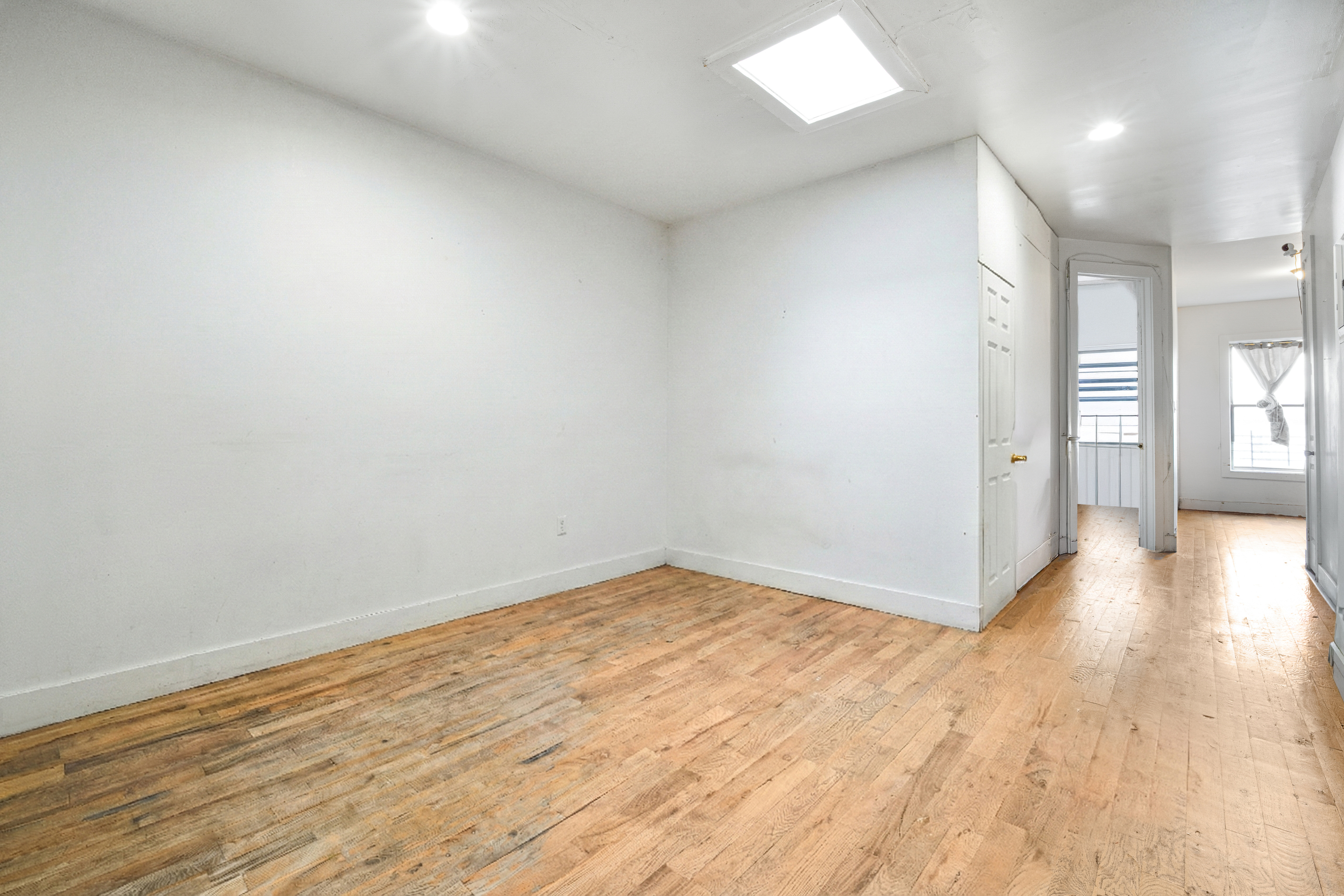 62-22 Myrtle Avenue Queens, NY 11385 - Photo 4 of 13 wooden floor in an empty room with a window