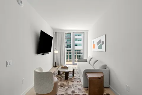 a living room with furniture a flat screen tv and a window