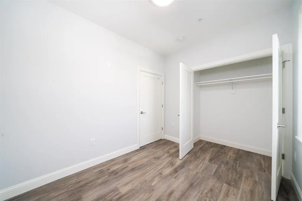 a view of an empty room with wooden floor and closet