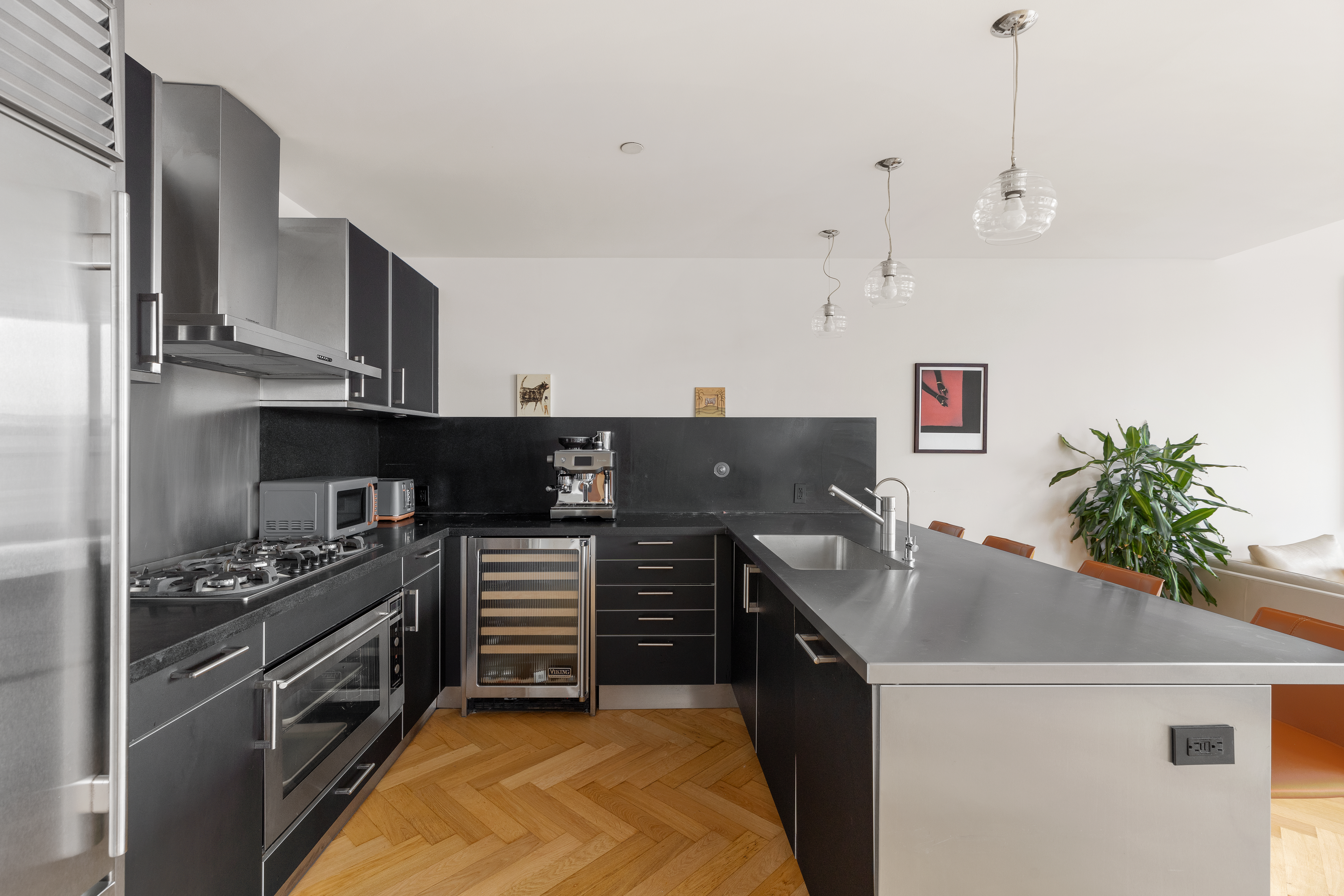 330 Spring Street, Unit 11B Manhattan, NY 10013 - Photo 3 of 10 a kitchen with kitchen island granite countertop stainless steel appliances and wooden cabinets
