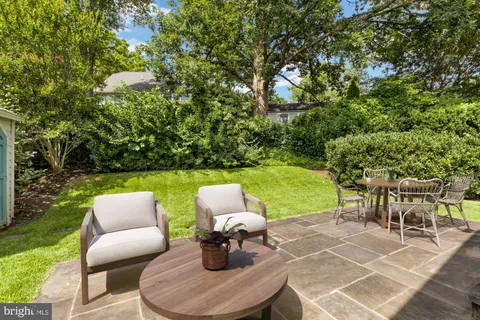 a couple of chairs sitting in a yard with large trees