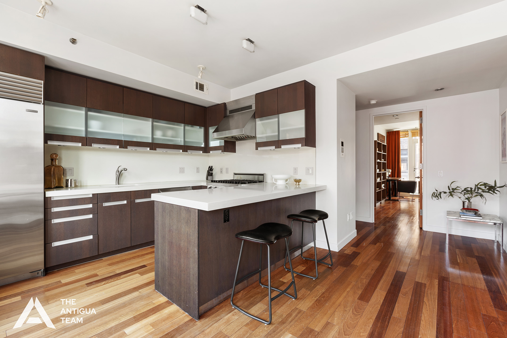 125 West 21st Street, Unit 12A Manhattan, NY 10011 - Photo 5 of 16 a kitchen with wooden floors and wooden cabinets