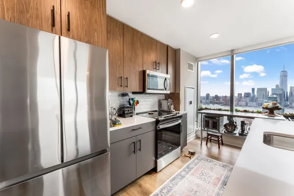 a large kitchen with stainless steel appliances a lot of counter space and a view of living room