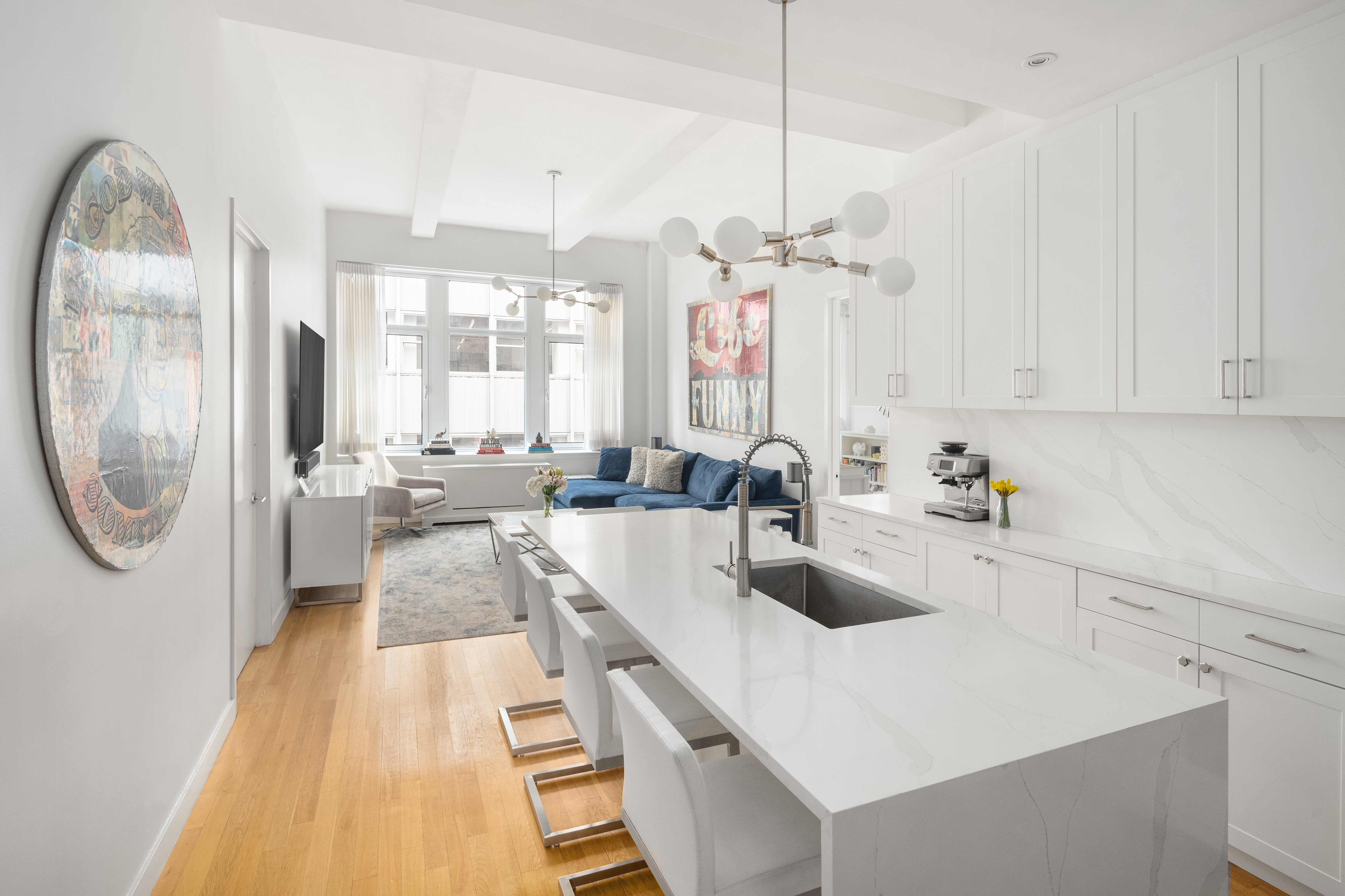 59 John Street, Unit 7D Manhattan, NY 10038 - Photo 3 of 10 a large kitchen with kitchen island a large counter space a sink a stove and a chandelier