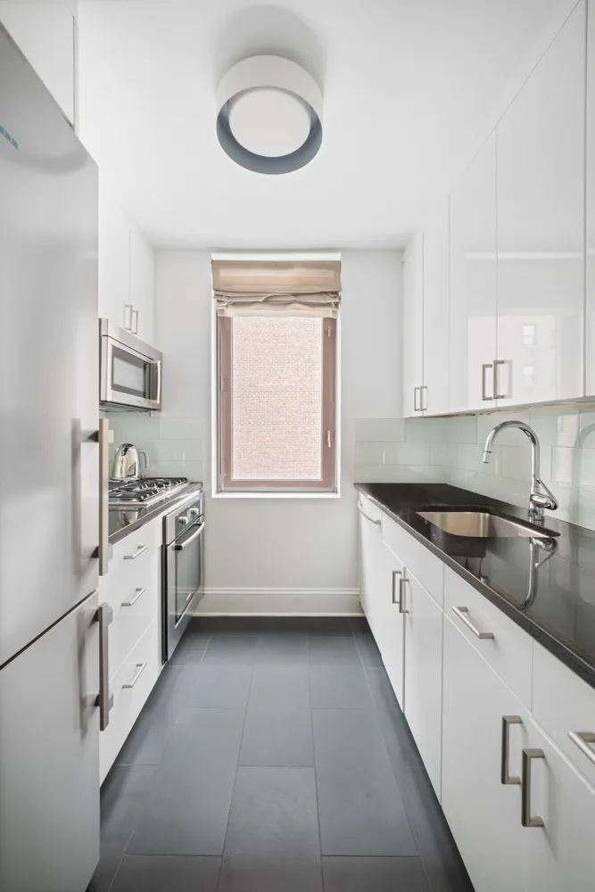 a large white kitchen with stainless steel appliances granite countertop a sink and dishwasher a stove top oven with white cabinets