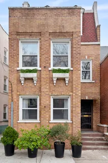 a front view of a brick house with potted plants