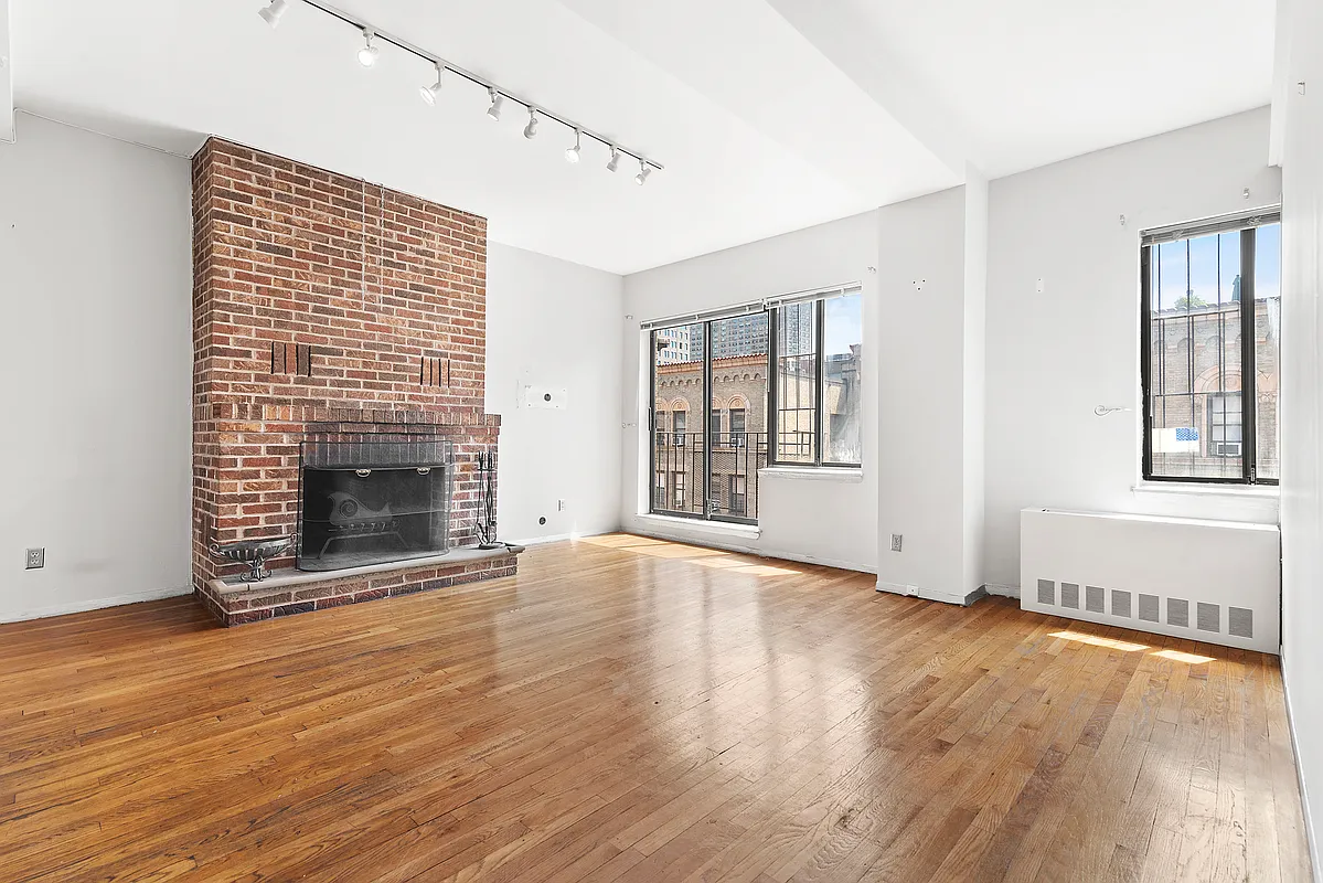 an empty room with wooden floor fireplace and windows