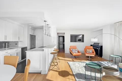 a living room with furniture a flat screen tv and kitchen view