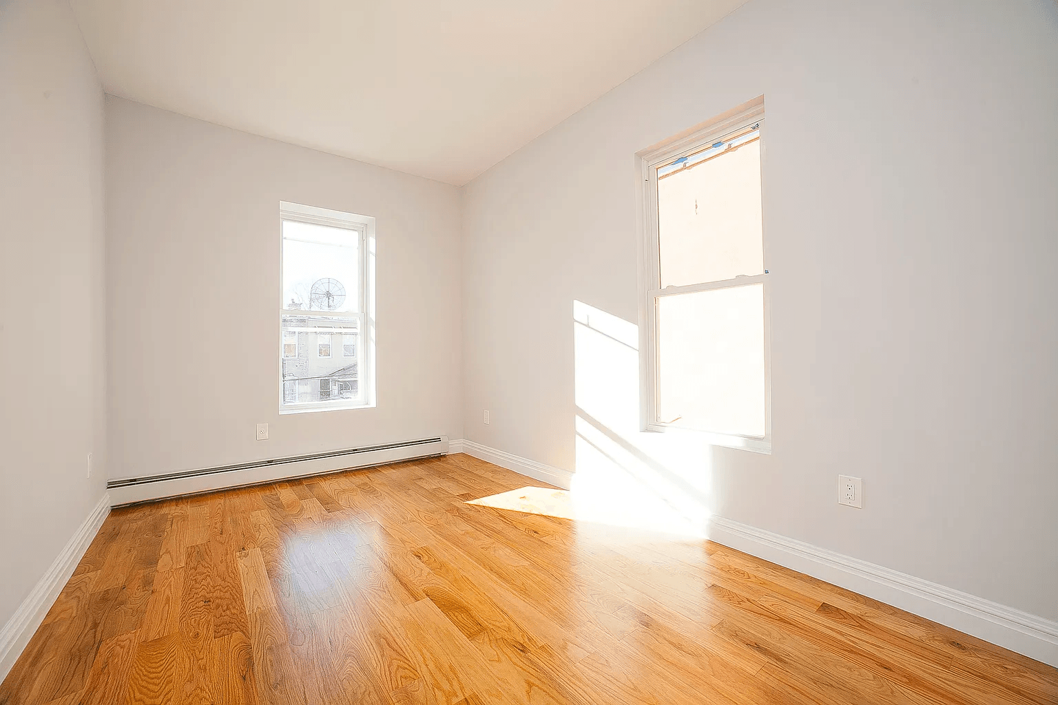 581 Van Siclen Avenue Brooklyn, NY 11207 - Photo 3 of 16 an empty room with wooden floor and windows
