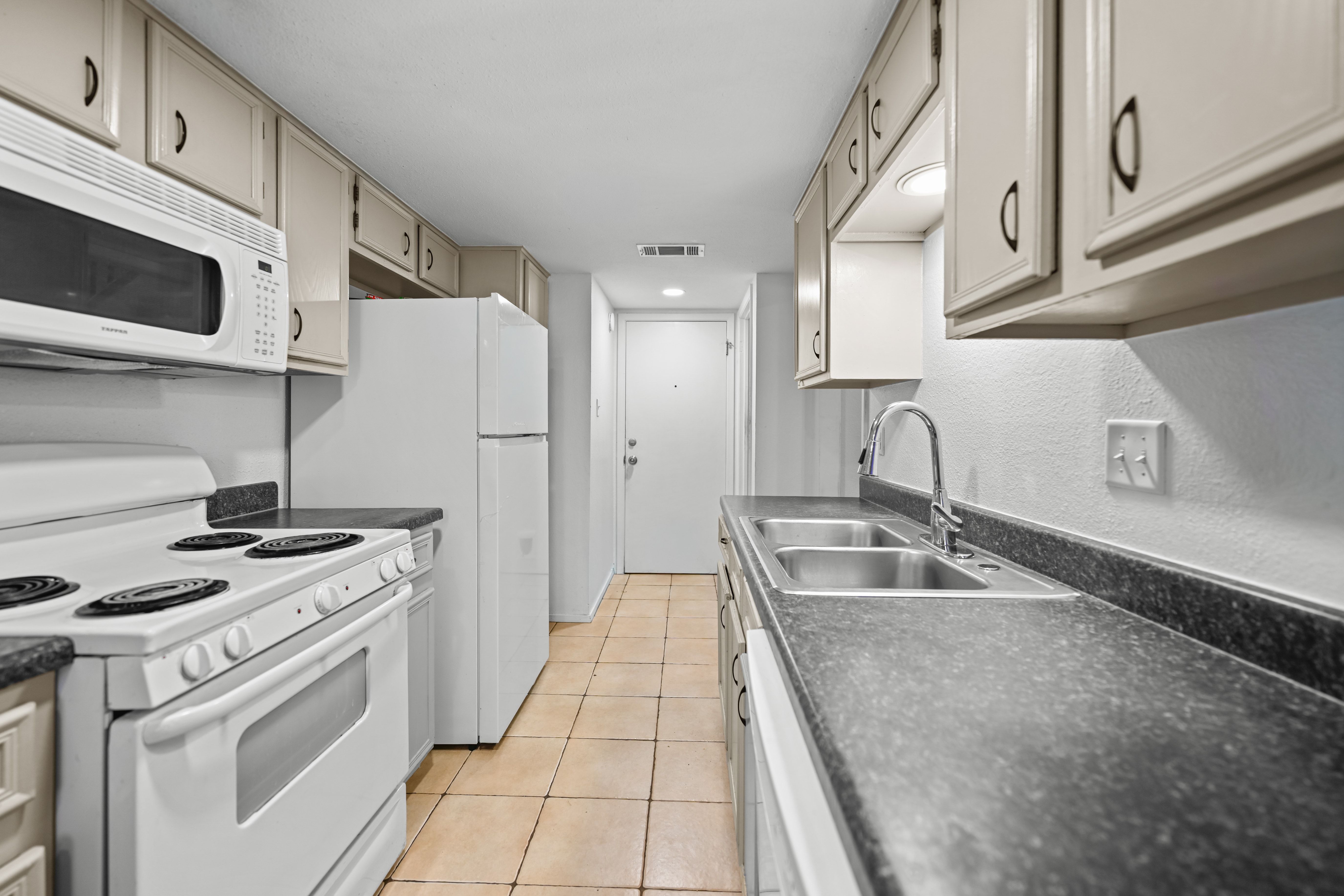8710 Clearbrook Trail Austin, TX 78729 - Photo 22 of 28 a kitchen with granite countertop a sink stove and refrigerator