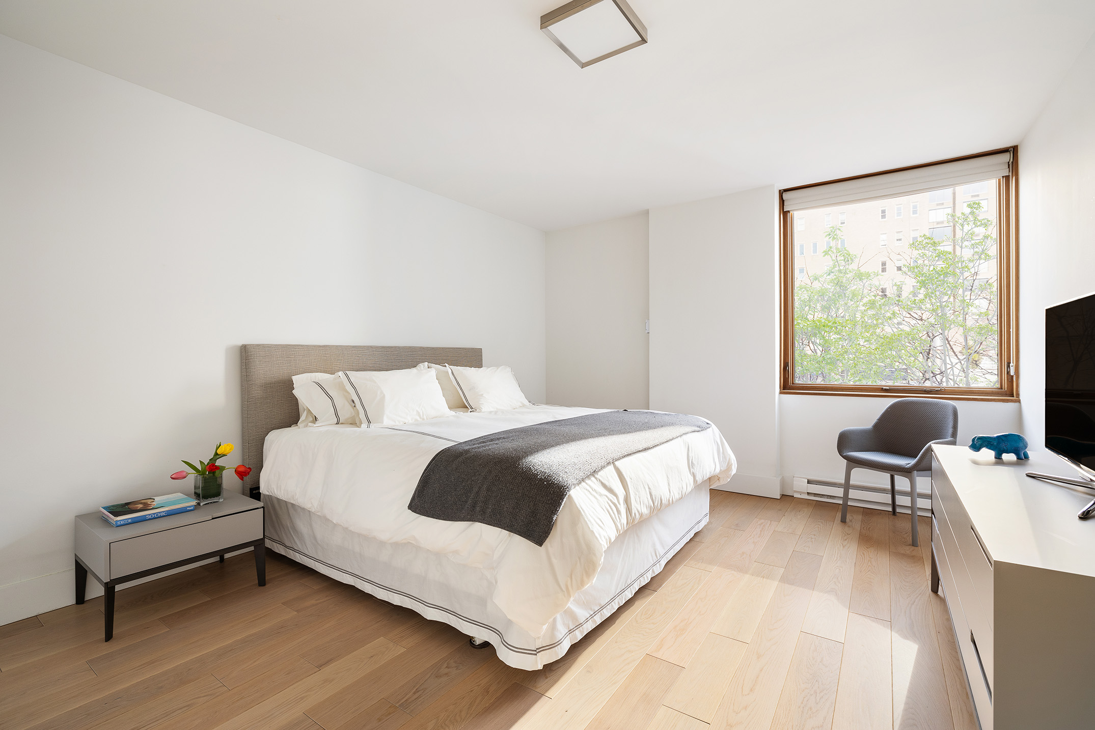 1080 Madison Avenue, Unit 6B Manhattan, NY 10028 - Photo 4 of 11 a bedroom with a bed wooden floor and lamp next to a window