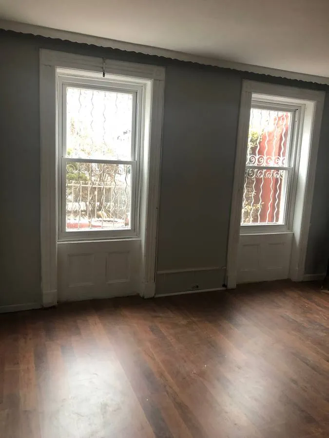 an empty room with wooden floor and windows