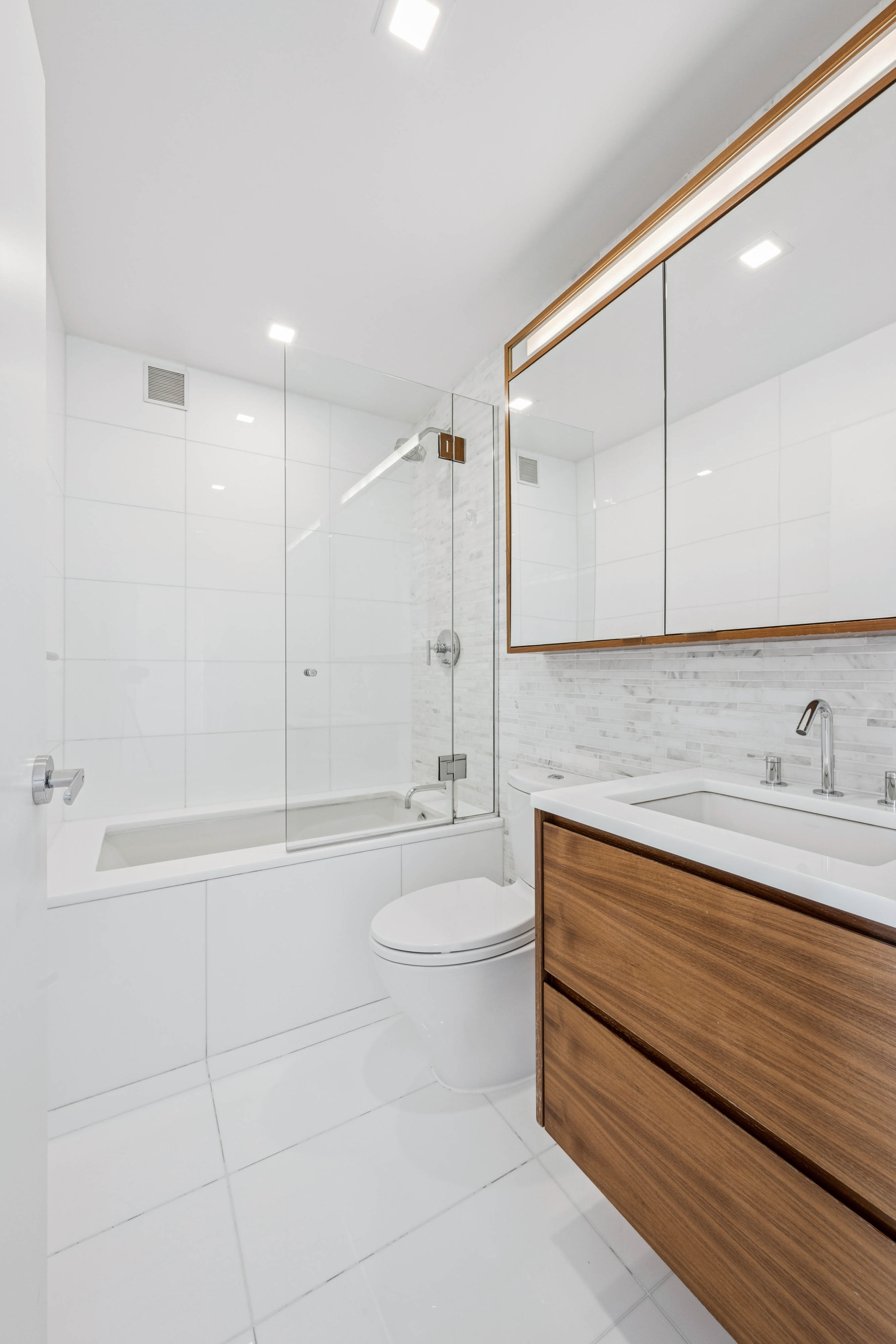 301 West 53rd Street, Unit 21B Manhattan, NY 10019 - Photo 5 of 20 a bathroom with a granite countertop sink a toilet and bathtub