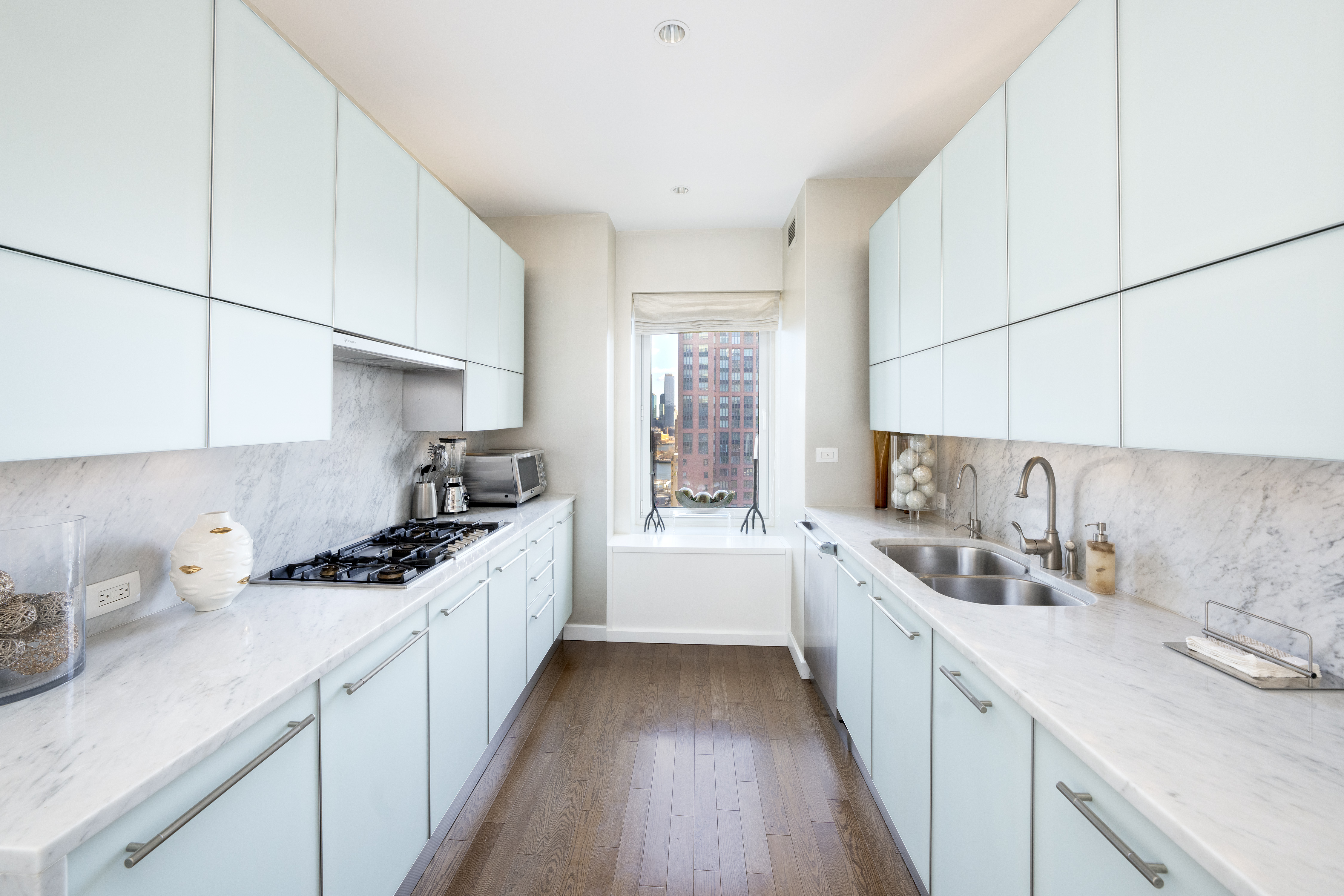 310 East 53rd Street, Unit 18A Manhattan, NY 10022 - Photo 9 of 19 a kitchen with a sink stove cabinets and wooden floor