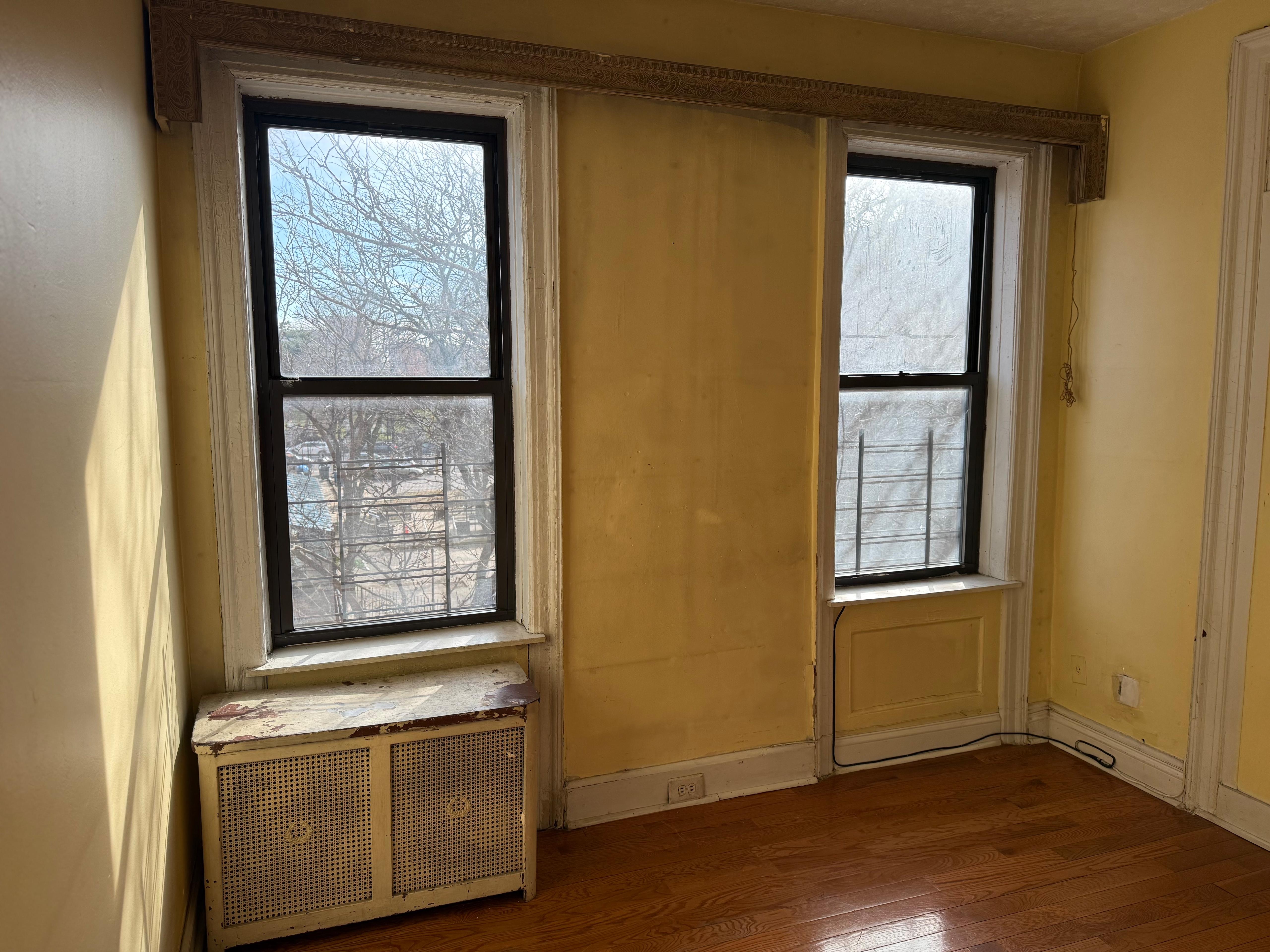 501 West 156th Street Manhattan, NY 10032 - Photo 3 of 4 an empty room with wooden floor and windows