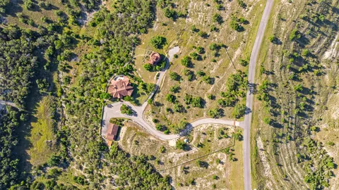 an aerial view of residential houses with outdoor space and trees