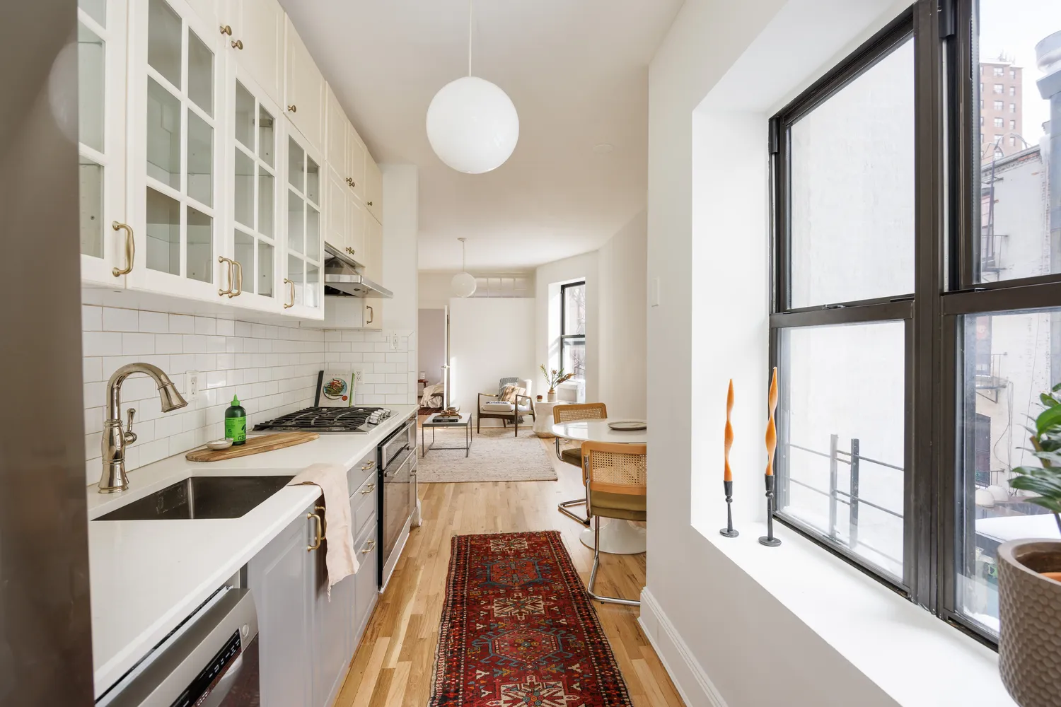 a kitchen with stainless steel appliances a sink a stove and a view of living room
