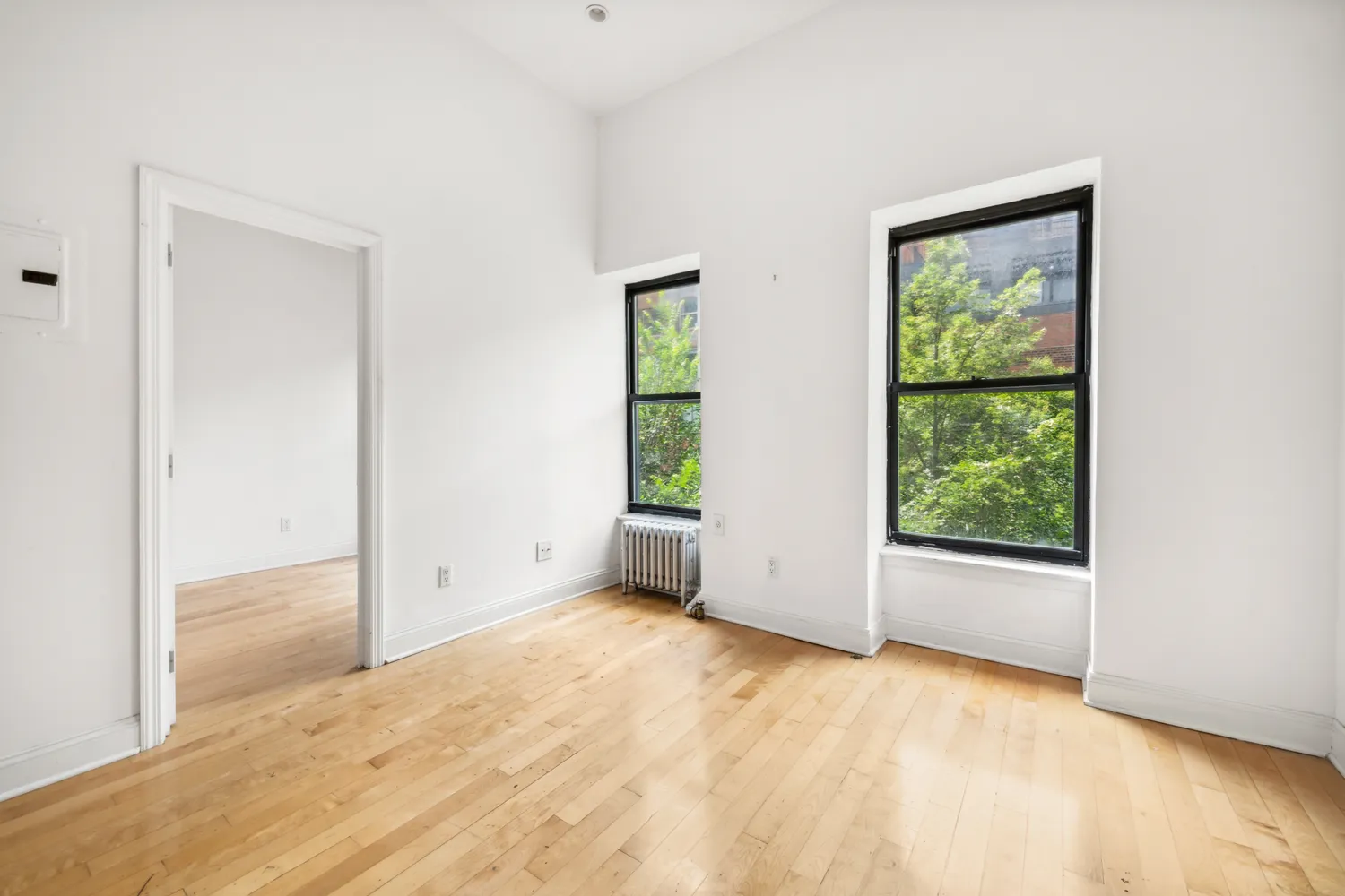 a view of an empty room with wooden floor and a window