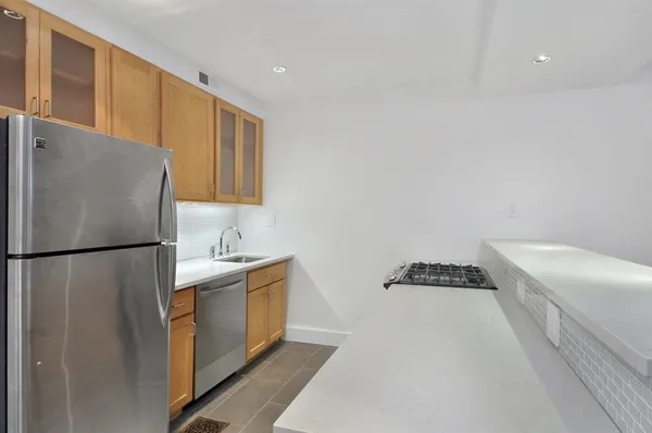a kitchen with stainless steel appliances a refrigerator a sink and white cabinets
