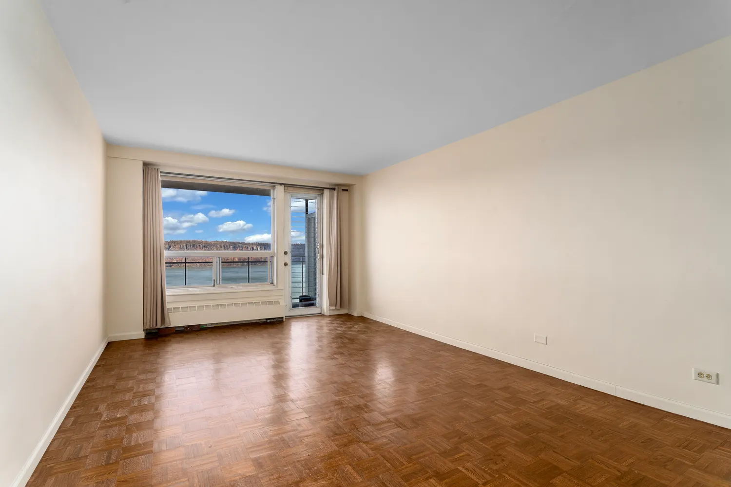 a view of an empty room with a window and wooden floor