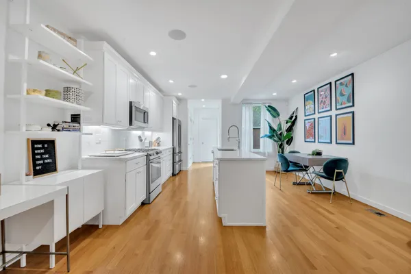 a large white kitchen with wooden floor and a refrigerator