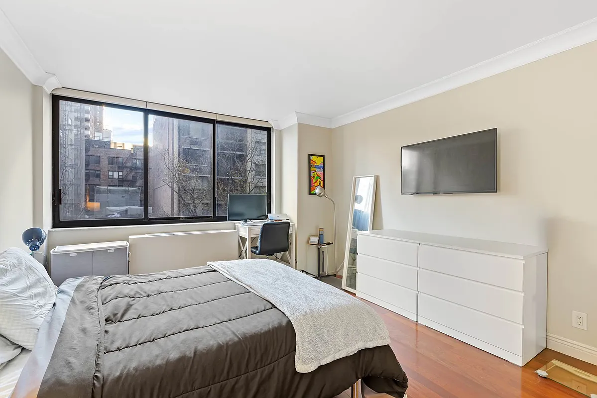510 East 80th Street, Unit 4D Manhattan, NY 10075 - Photo 9 of 20 a bedroom with a large bed and a flat tv screen on dresser
