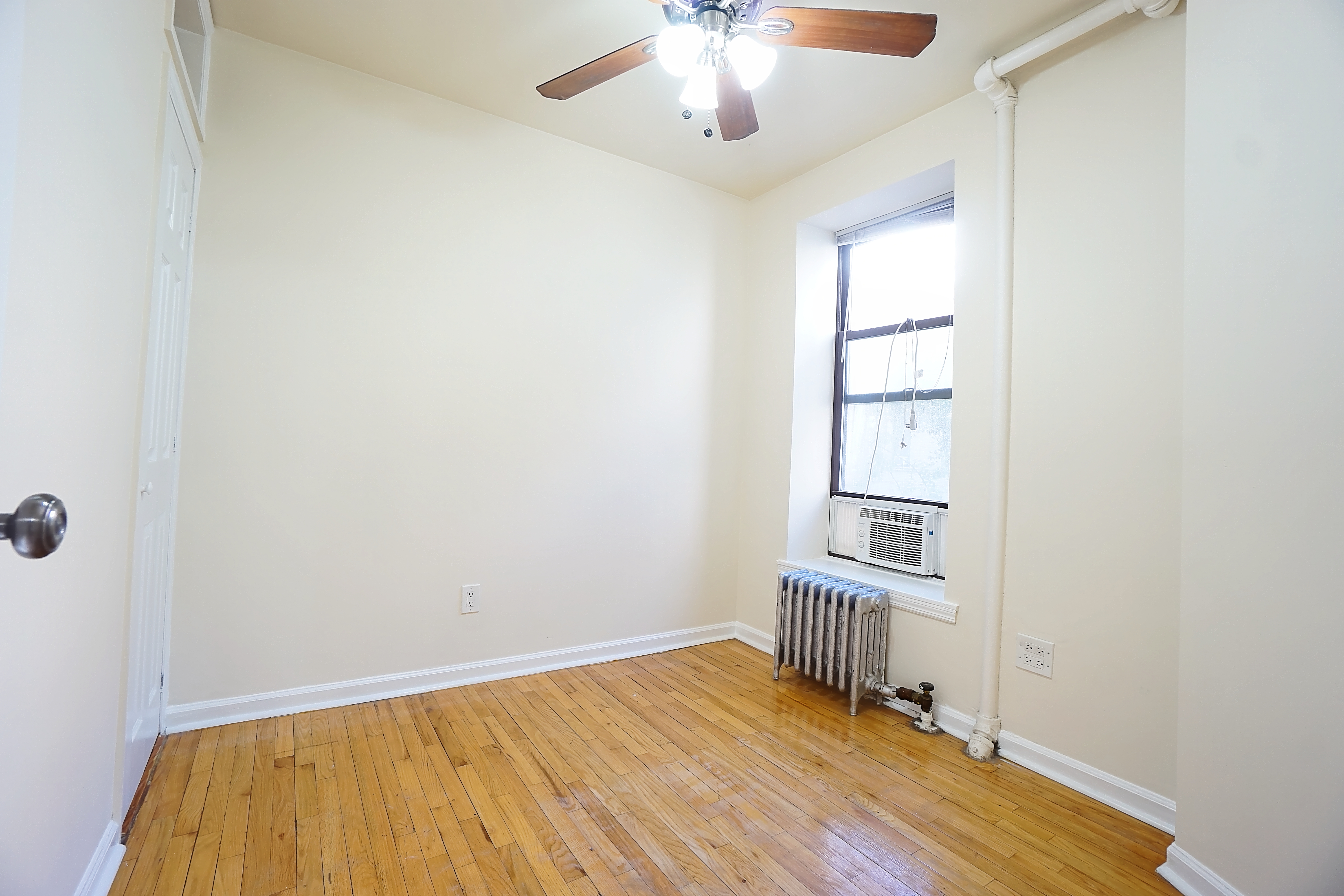 270 East 78th Street, Unit 10 Manhattan, NY 10075 - Photo 4 of 6 an empty room with wooden floor chandelier and windows