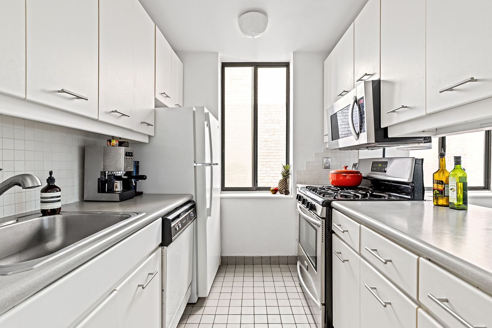 167 Perry Street, Unit 5F Manhattan, NY 10014 - Photo 5 of 12 a kitchen with stainless steel appliances granite countertop a sink dishwasher refrigerator stove and white cabinets
