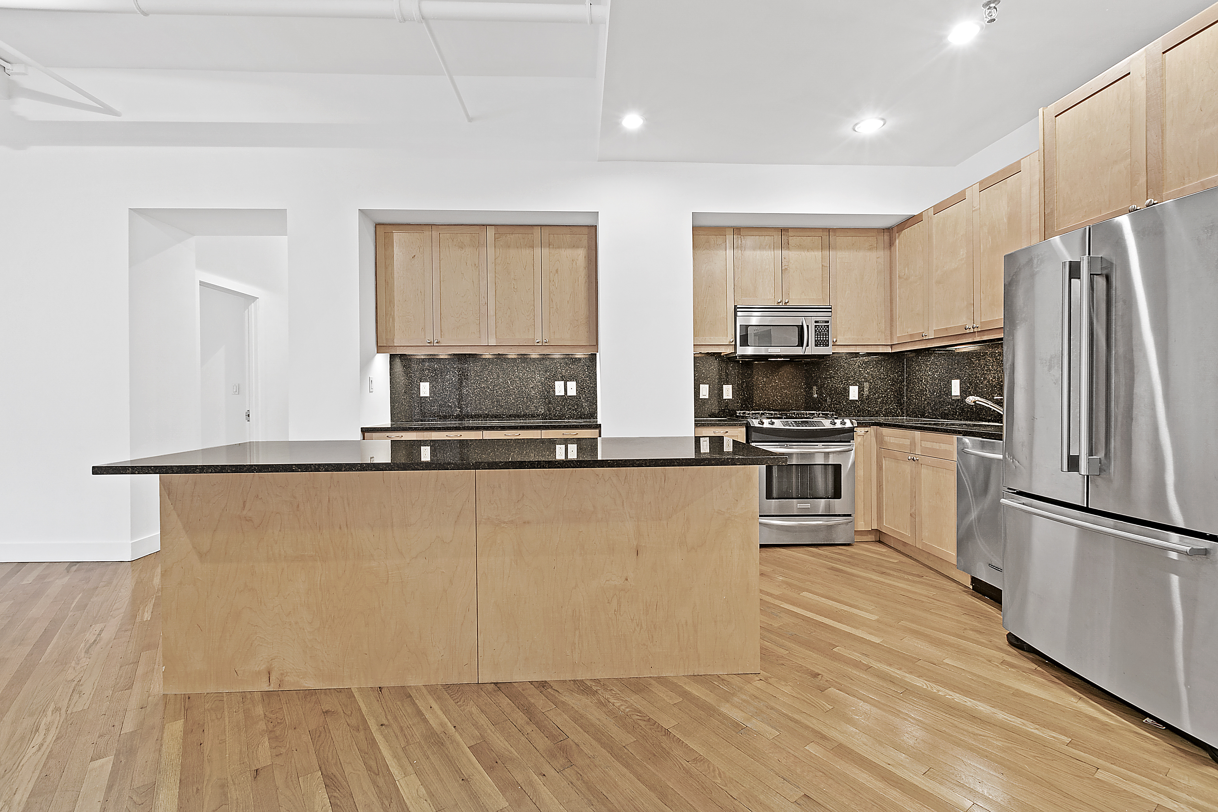 40 West 17th Street, Unit 3B Manhattan, NY 10011 - Photo 3 of 7 a kitchen with kitchen island a counter top space a sink wooden floor and stainless steel appliances