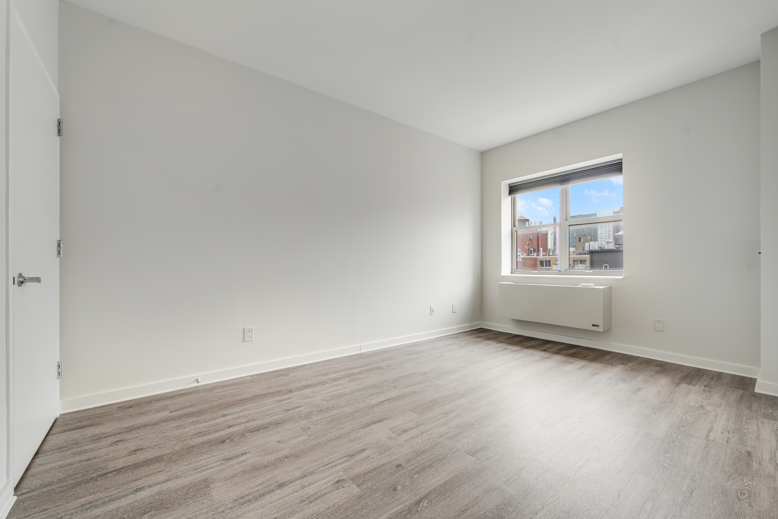516 West 47th Street, Unit N7A Manhattan, NY 10036 - Photo 7 of 19 an empty room with wooden floor and windows
