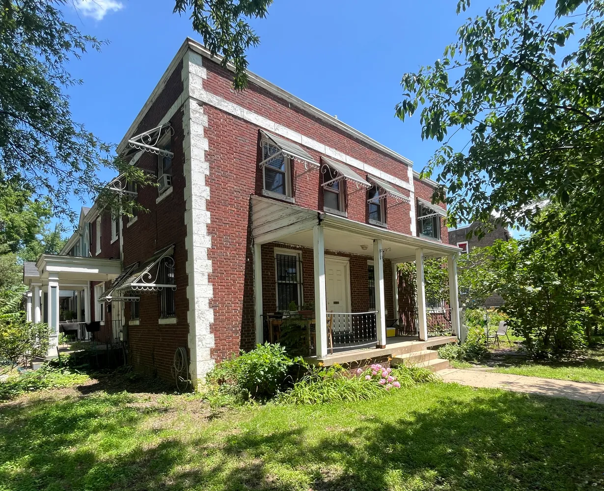 a view of a house with brick walls and a yard with plants