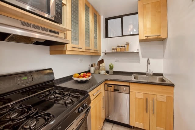 205 West 54th Street, Unit 2E Manhattan, NY 10019 - Photo 4 of 11 a kitchen with stainless steel appliances granite countertop a stove and a sink