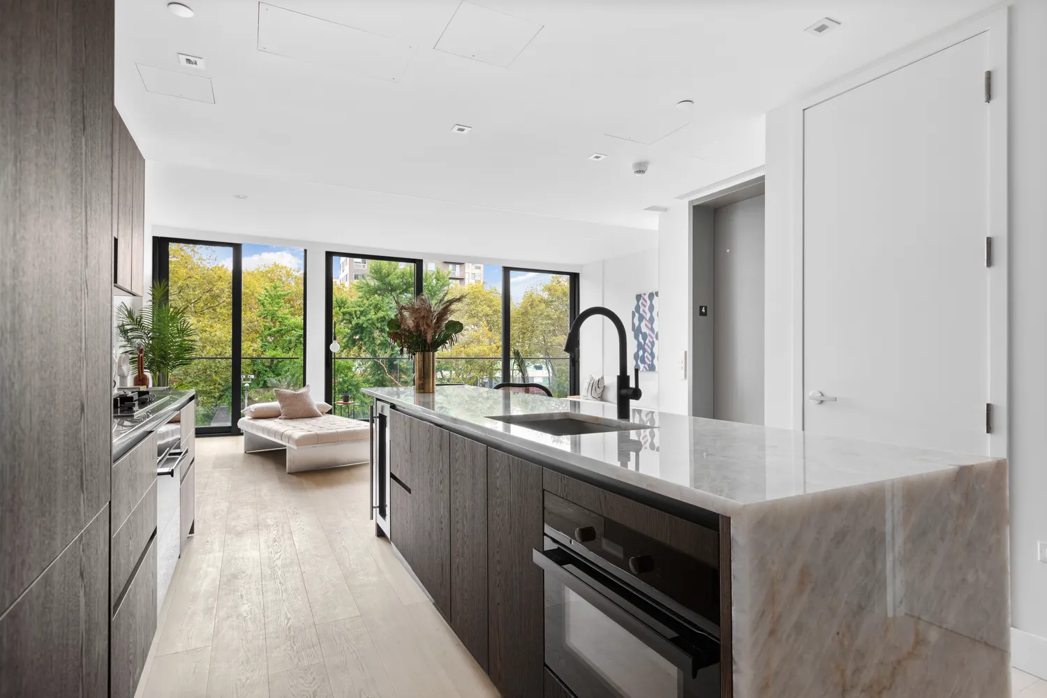 a kitchen with sink a large window and view of living room