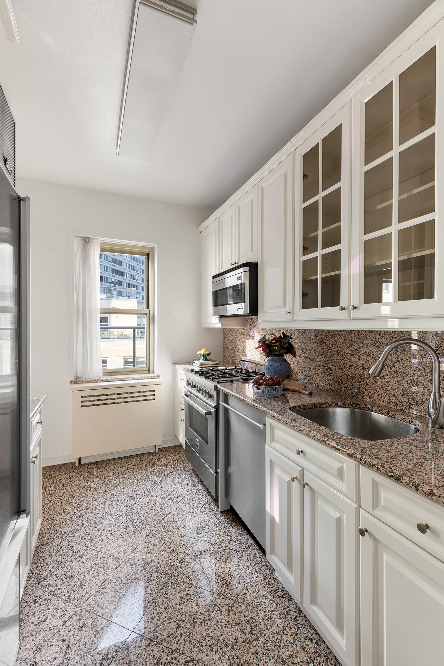 415 East 52nd Street, Unit 12CB Manhattan, NY 10022 - Photo 6 of 12 a kitchen with stainless steel appliances granite countertop a stove a sink and a granite counter tops