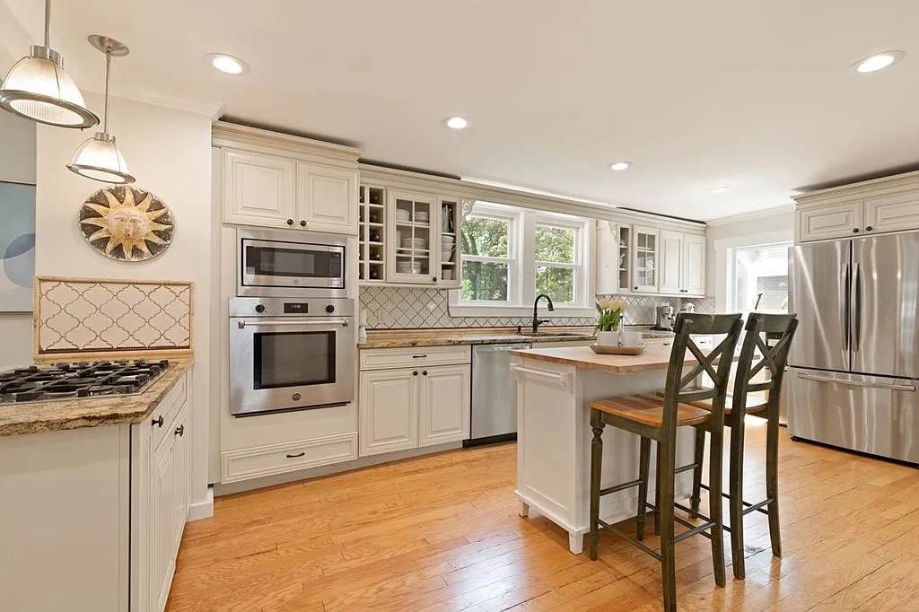 288 Albion Street Wakefield, MA 01880 - Photo 3 of 8 a kitchen with stainless steel appliances granite countertop a stove top oven a sink a dining table and chairs with wooden floor