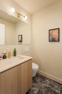 a bathroom with a granite countertop sink toilet and a mirror