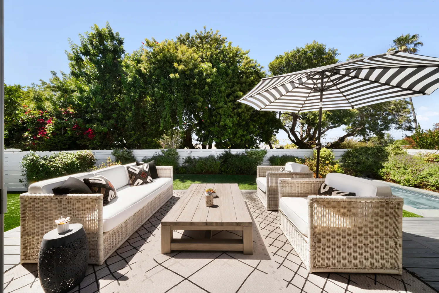 a view of a patio with couches table and chairs under an umbrella with a fire pit