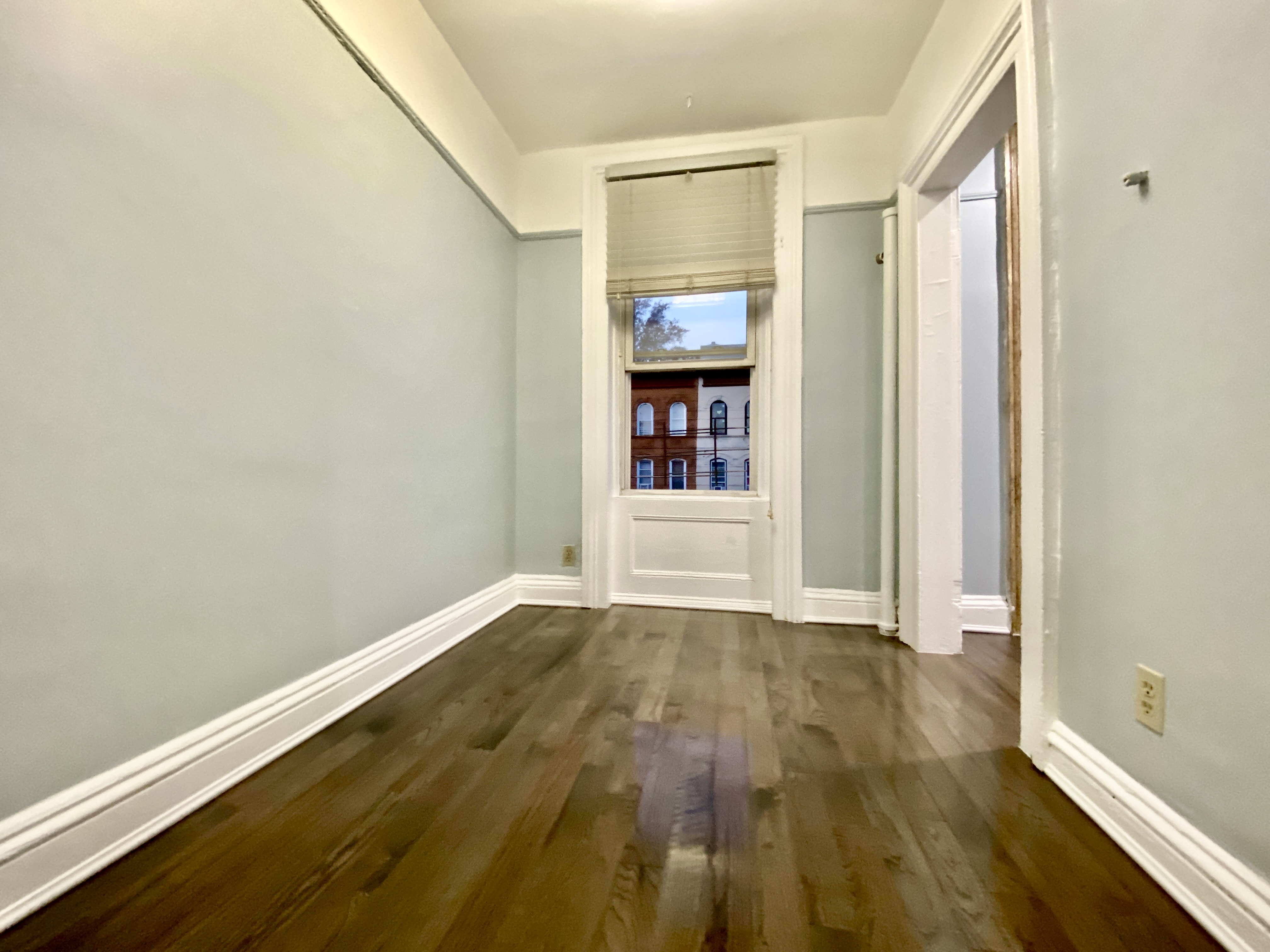 398 Decatur Street, Unit 3 Brooklyn, NY 11233 - Photo 7 of 9 a view of an empty room with wooden floor and a window