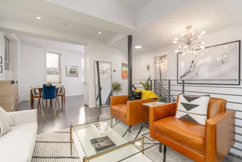 a living room with furniture a chandelier and a dining table