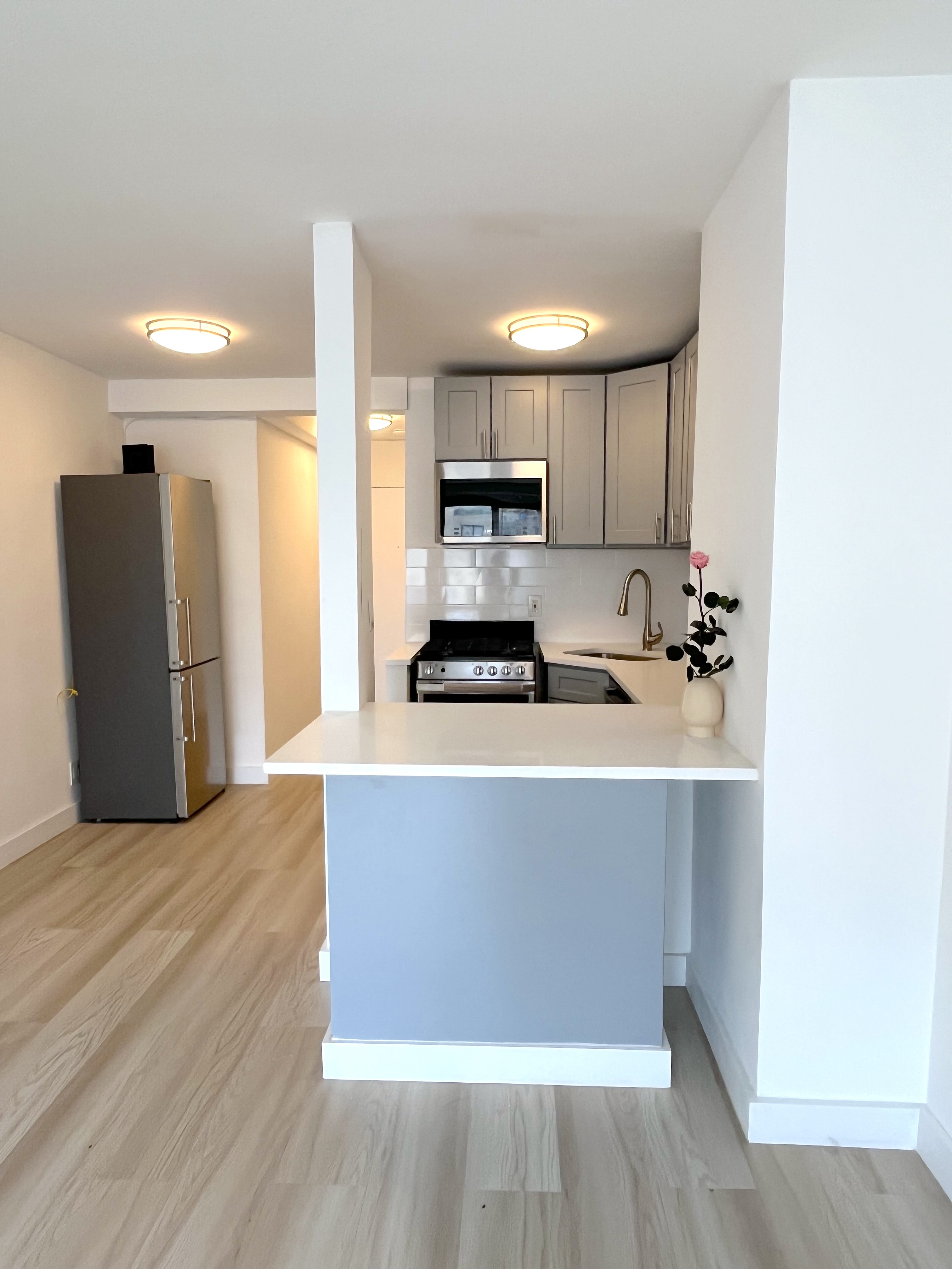 321 East 48th Street, Unit 10L Manhattan, NY 10017 - Photo 2 of 6 a kitchen with a refrigerator and a stove top oven