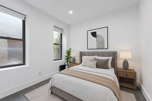 a bedroom with a large bed and two windows